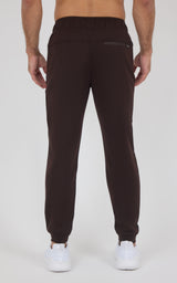 Dark brown men’s jogger pants with a tapered fit, elastic cuffs, and a back pocket, shown from behind.