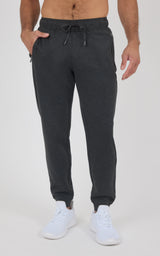 Dark charcoal men’s jogger pants with a drawstring waist, tapered legs, and elastic cuffs, paired with white sneakers.