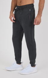 Men’s black tapered joggers with an elastic drawstring waist, side pockets, and ribbed ankle cuffs, worn with white sneakers.