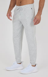 Men’s light gray joggers with a soft-looking knit finish, drawstring waistband, tapered cuffs, and white sneakers.