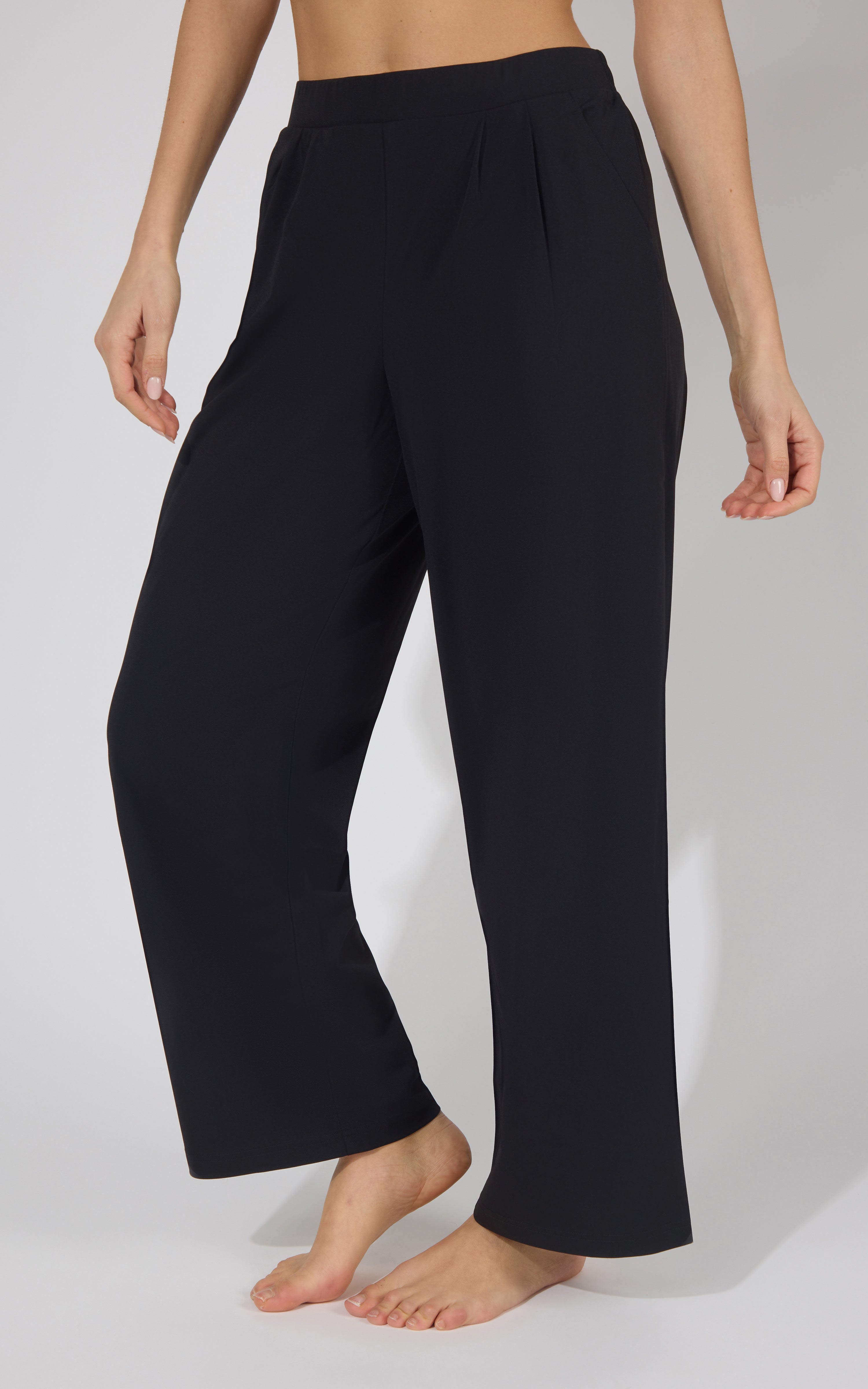 Black wide-leg trousers with pleats and a straight fit on a woman.