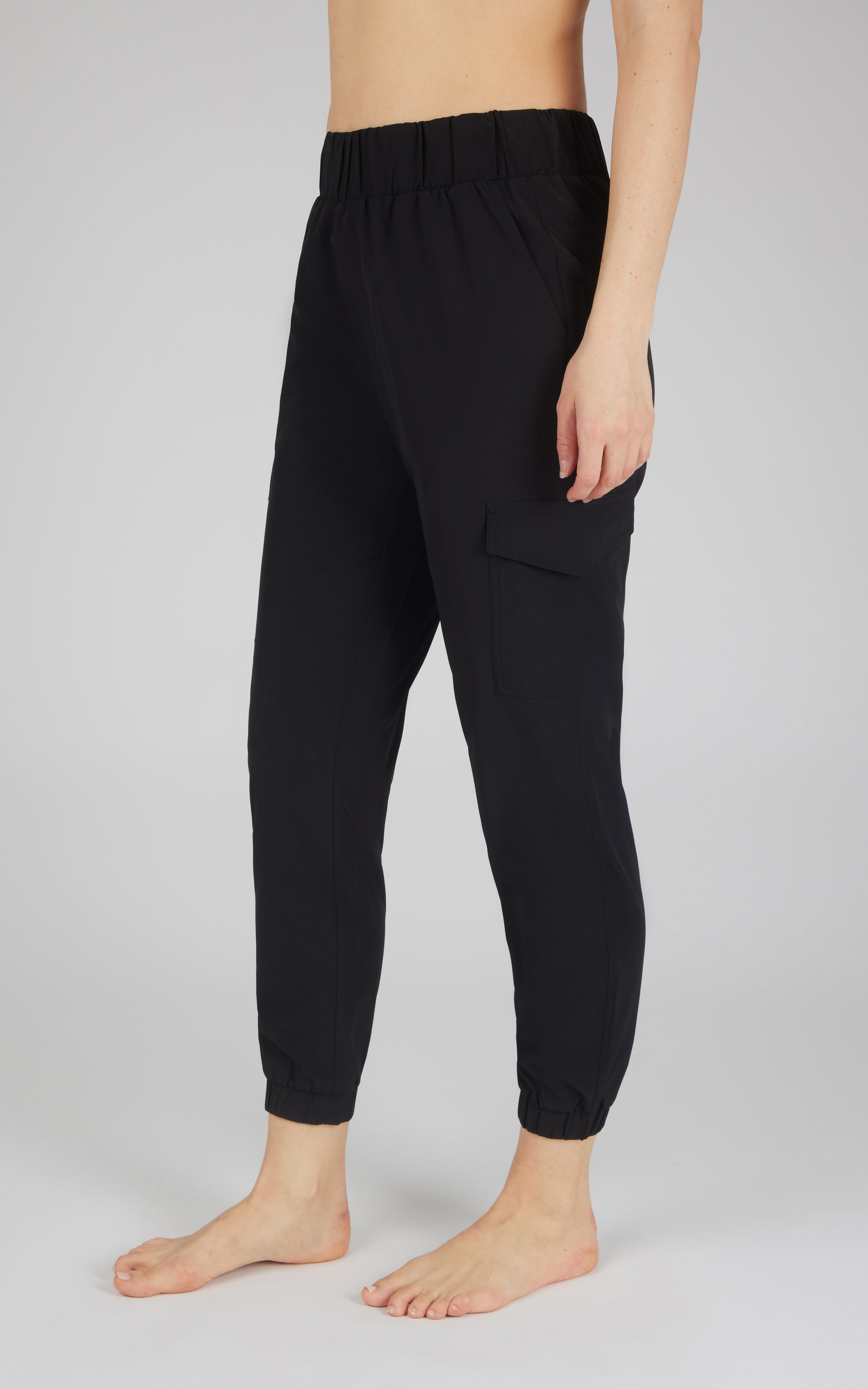 Black cargo jogger pants with side pocket and elastic cuffs on barefoot model.