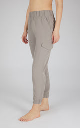 Gray tapered cargo joggers with elastic waistband and side flap pocket on woman’s legs.