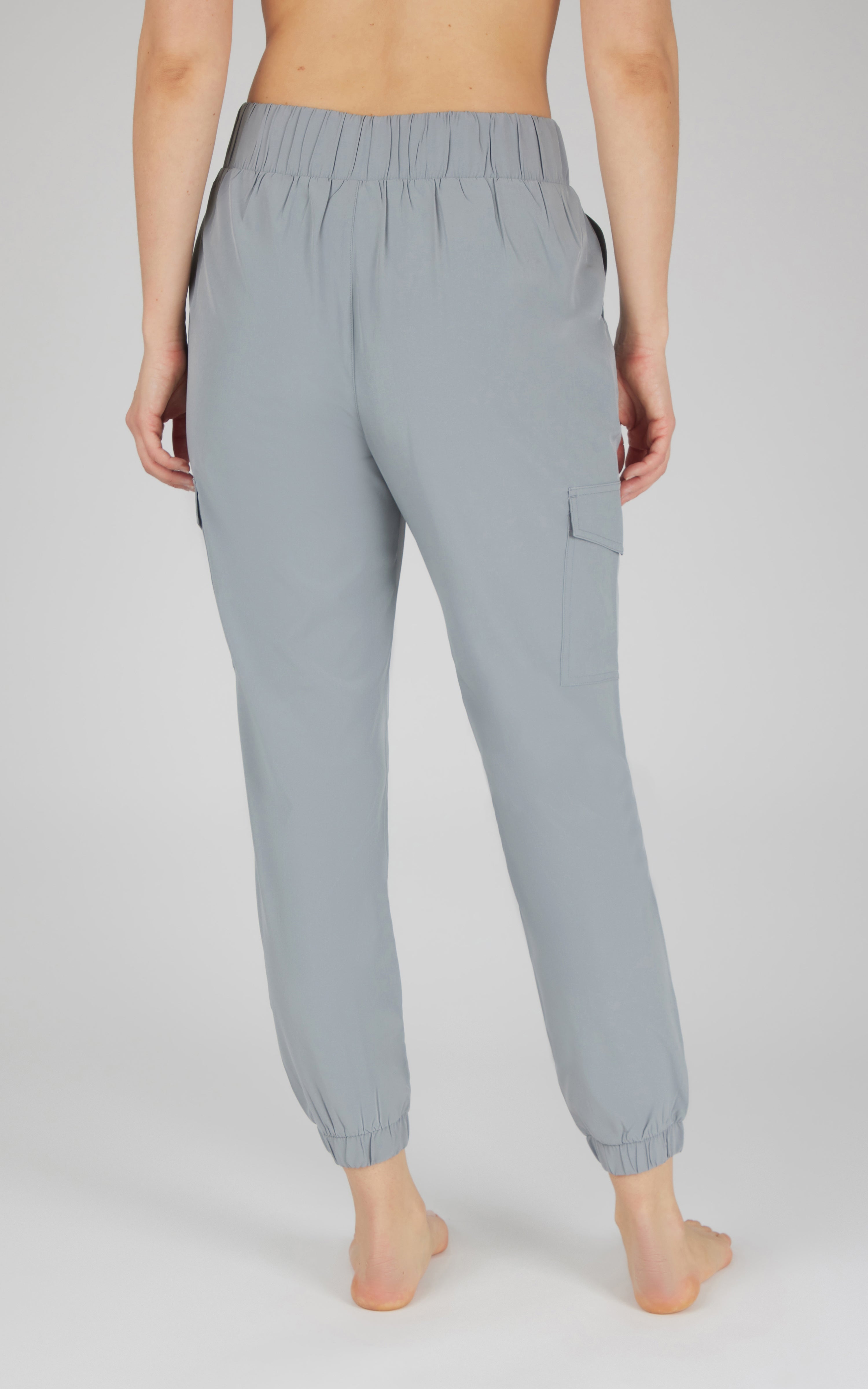 Light gray cargo joggers with elastic waistband, side pockets, and cuffed ankles on model's back view.