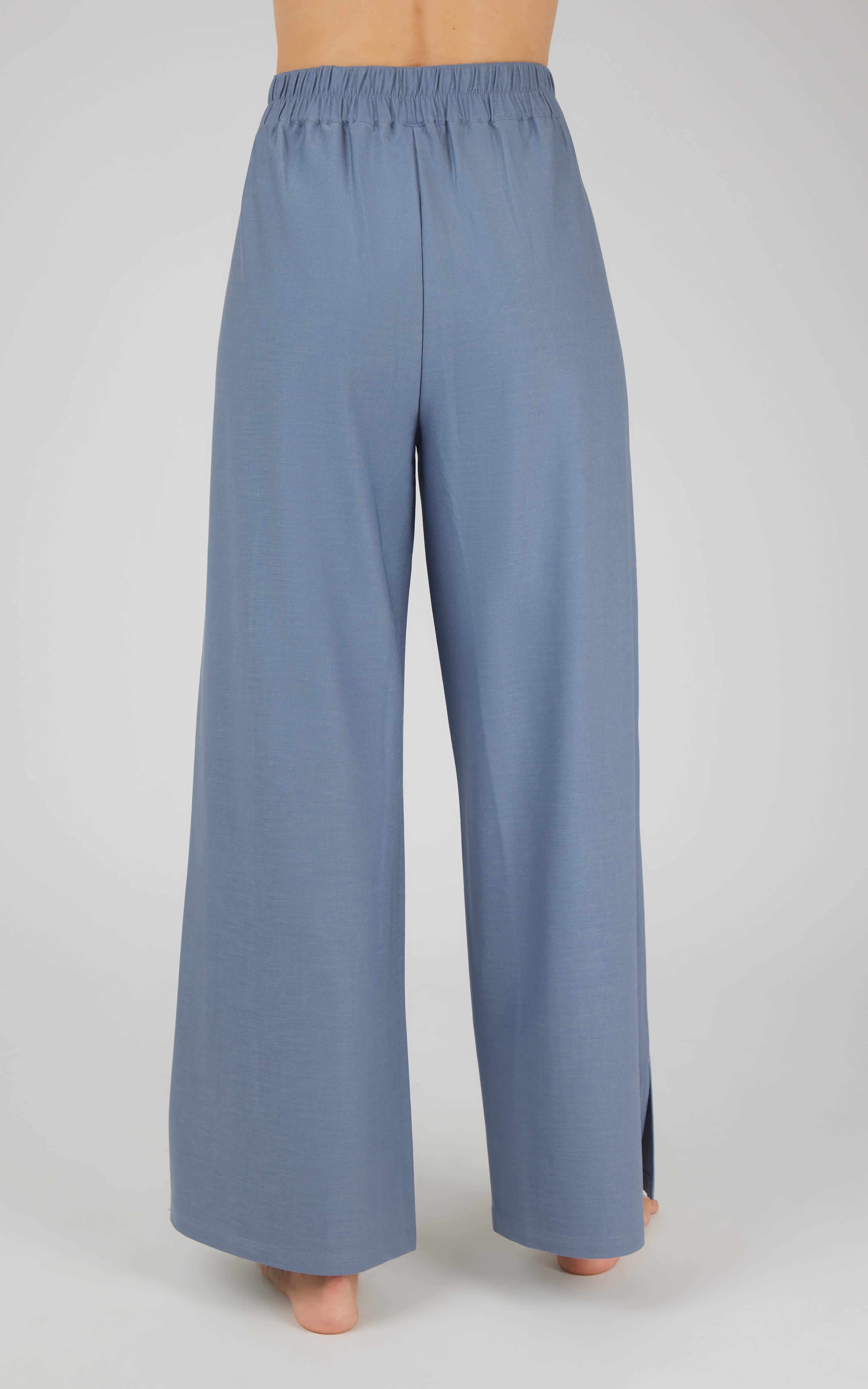 Women's wide leg pants in muted blue with elastic waistband and small side slits at hem.