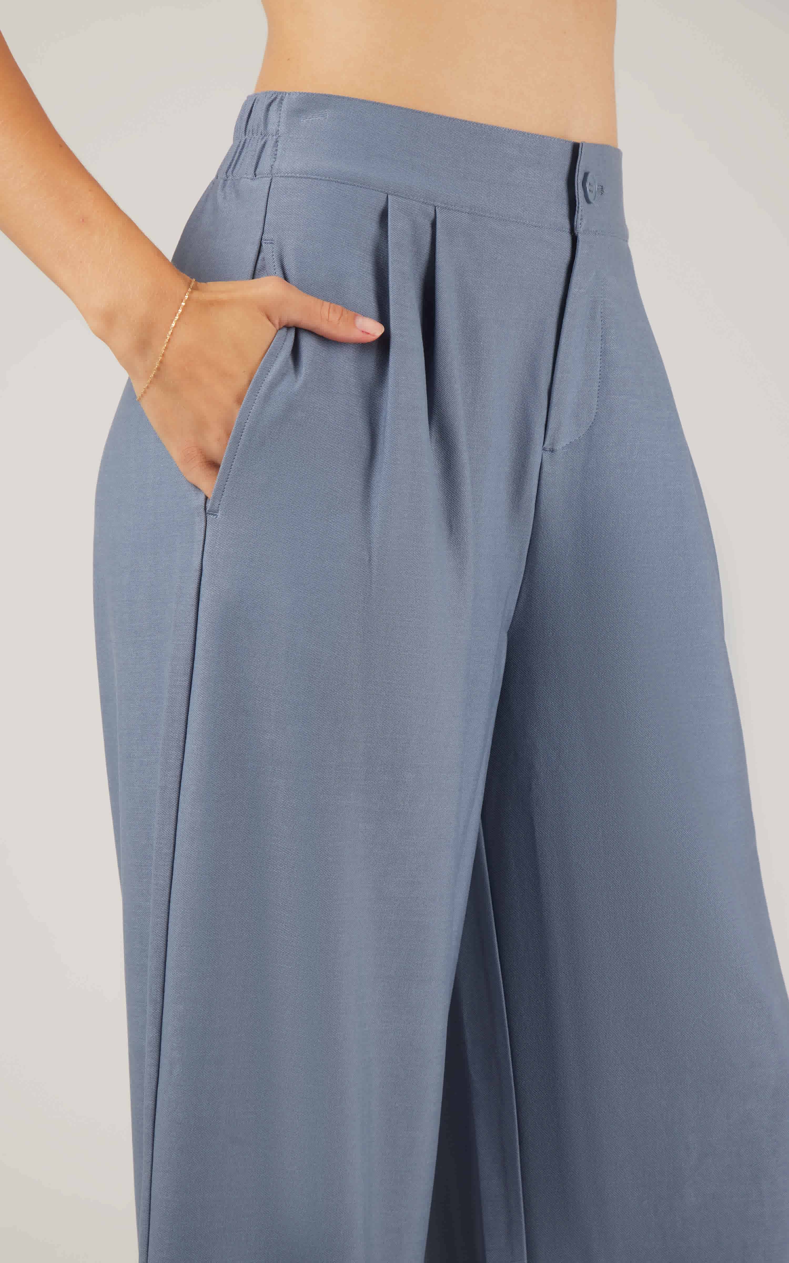 High-waist light blue pleated wide-leg denim pants with side pockets and button closure.