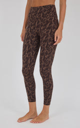 A model wearing brown and black leopard print leggings, shown from the waist down against a light gray studio background.