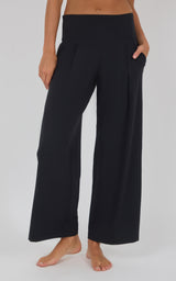 Black high-waisted wide-leg trousers with a smooth finish, flowing drape, and side pockets.