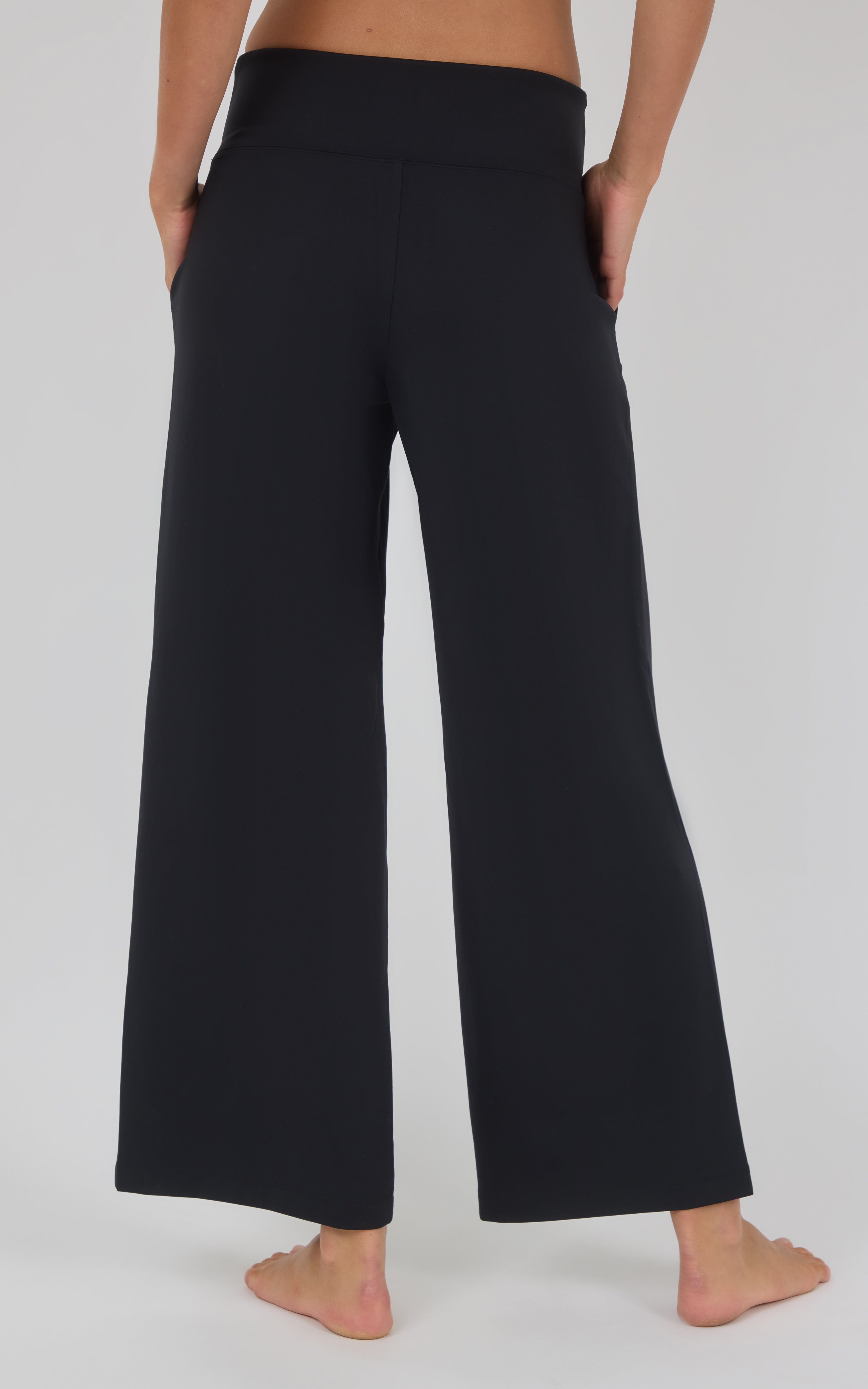 Black high-waisted wide-leg trousers with a smooth, tailored finish, shown cropped above the waist.