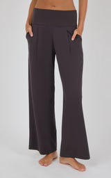 Dark charcoal wide-leg trousers with a smooth drape, front pleats, and a floor-length cropped-model fit.