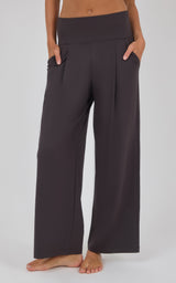 Dark charcoal wide-leg trousers with a high-rise waistband, front pleats, and a loose, flowing fit.