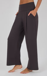 Dark charcoal wide-leg trousers with a high-rise waistband, front pleats, and side pockets, modeled barefoot.