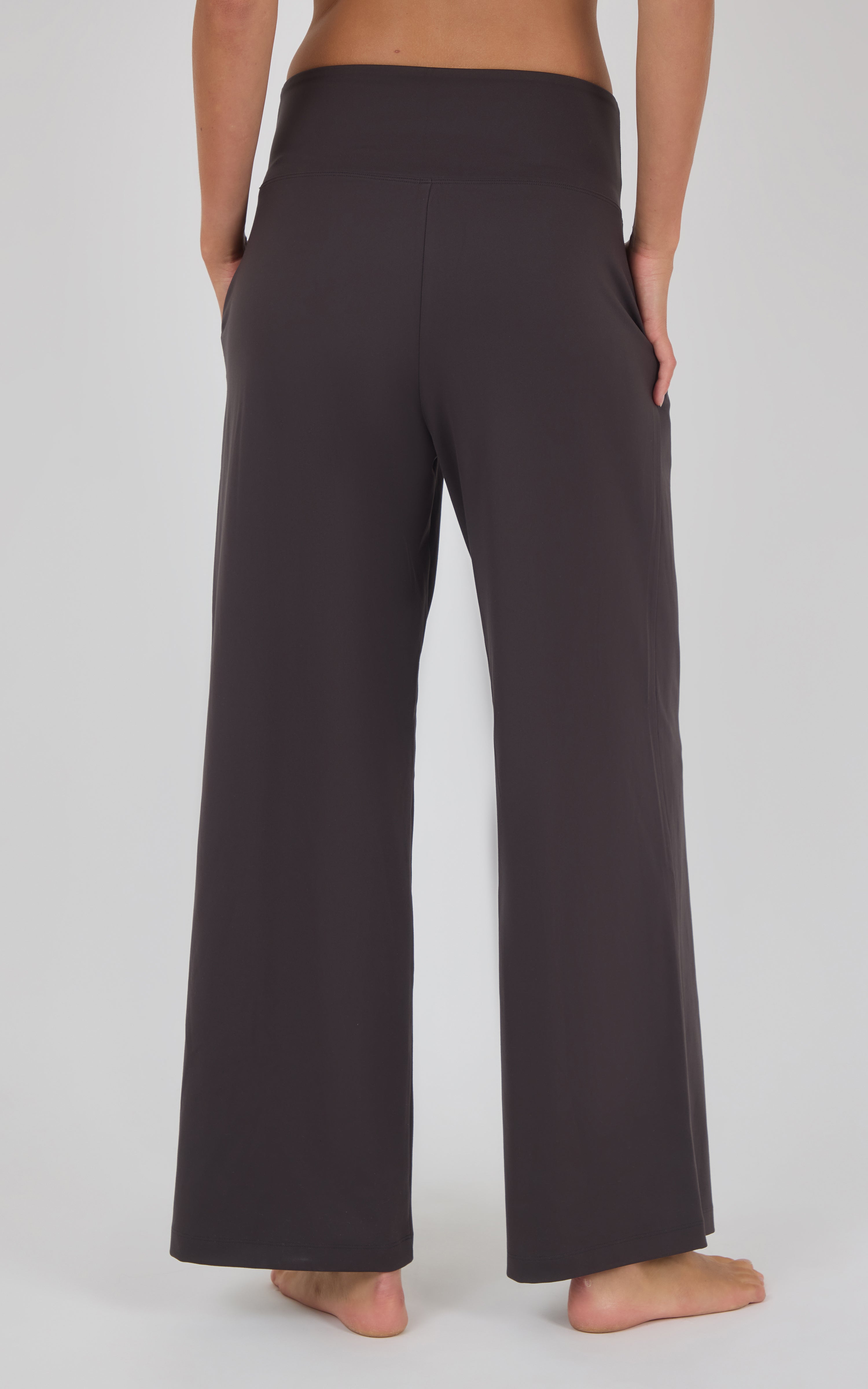 Dark charcoal wide-leg trousers with a high waist and subtle front pleats, shown from the back with a relaxed fit.