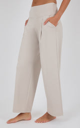 Ivory pleated wide-leg trousers with a high waist and relaxed fit, modeled with bare feet.