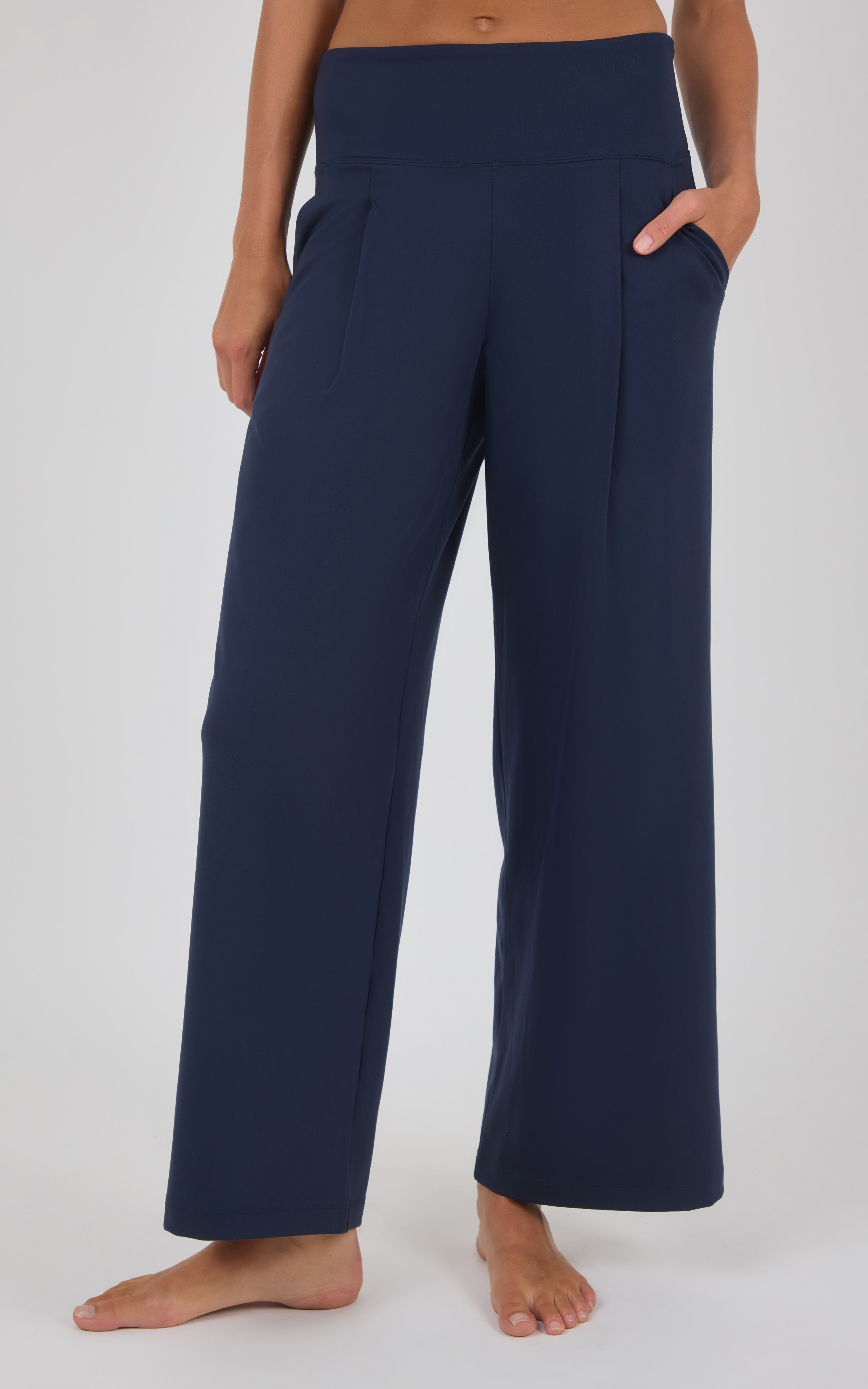 Navy wide-leg trousers with front pleats and a high waist, styled with a cropped top and bare feet.