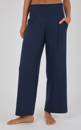 Navy wide-leg trousers with front pleats and a high waist, styled with a cropped top and bare feet.