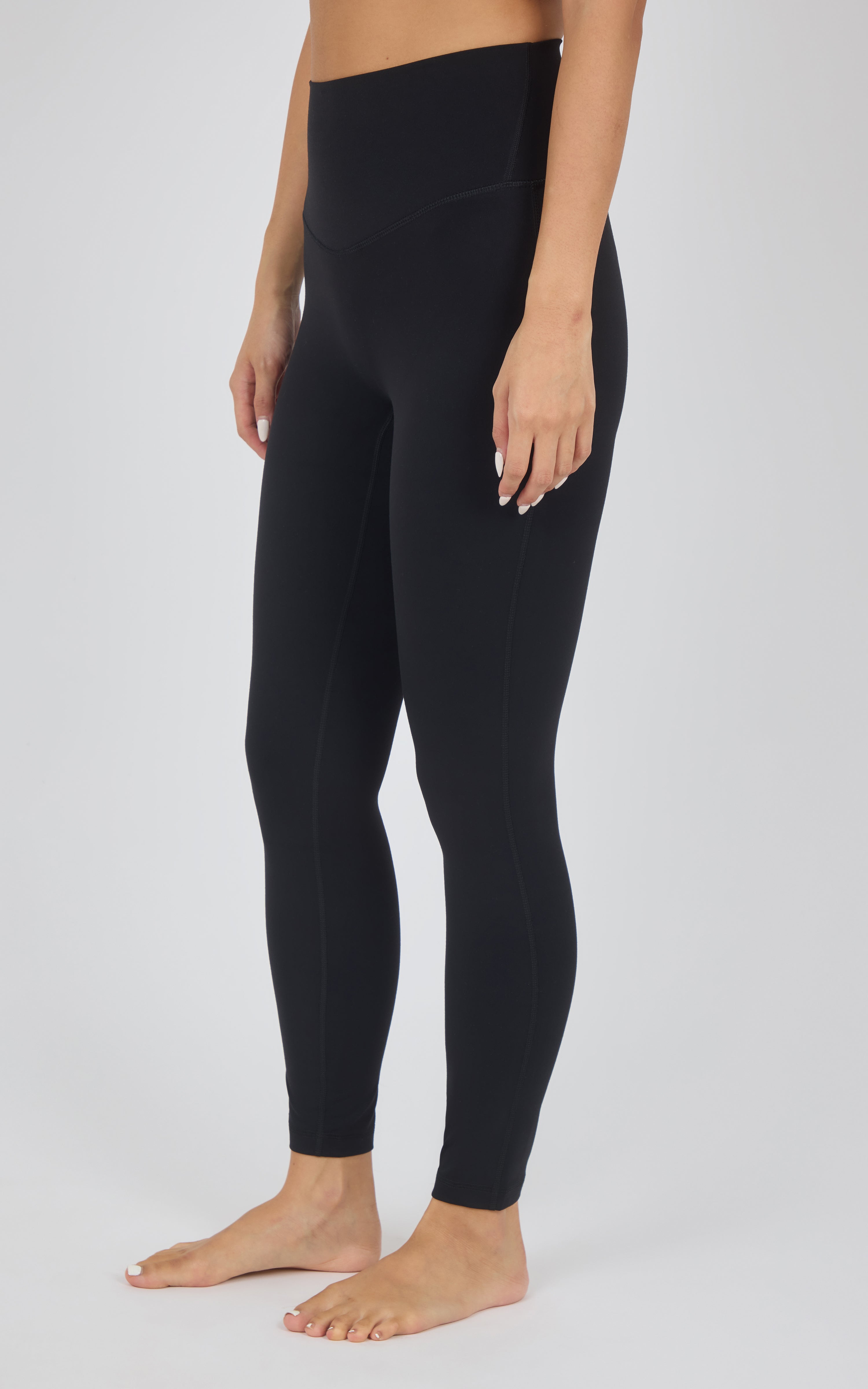 A model wearing black high-waisted leggings, shown from the waist down against a light gray studio background.