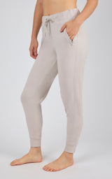 Light gray jogger pants with side pockets, drawstring waist, and ribbed cuffs on a standing model.