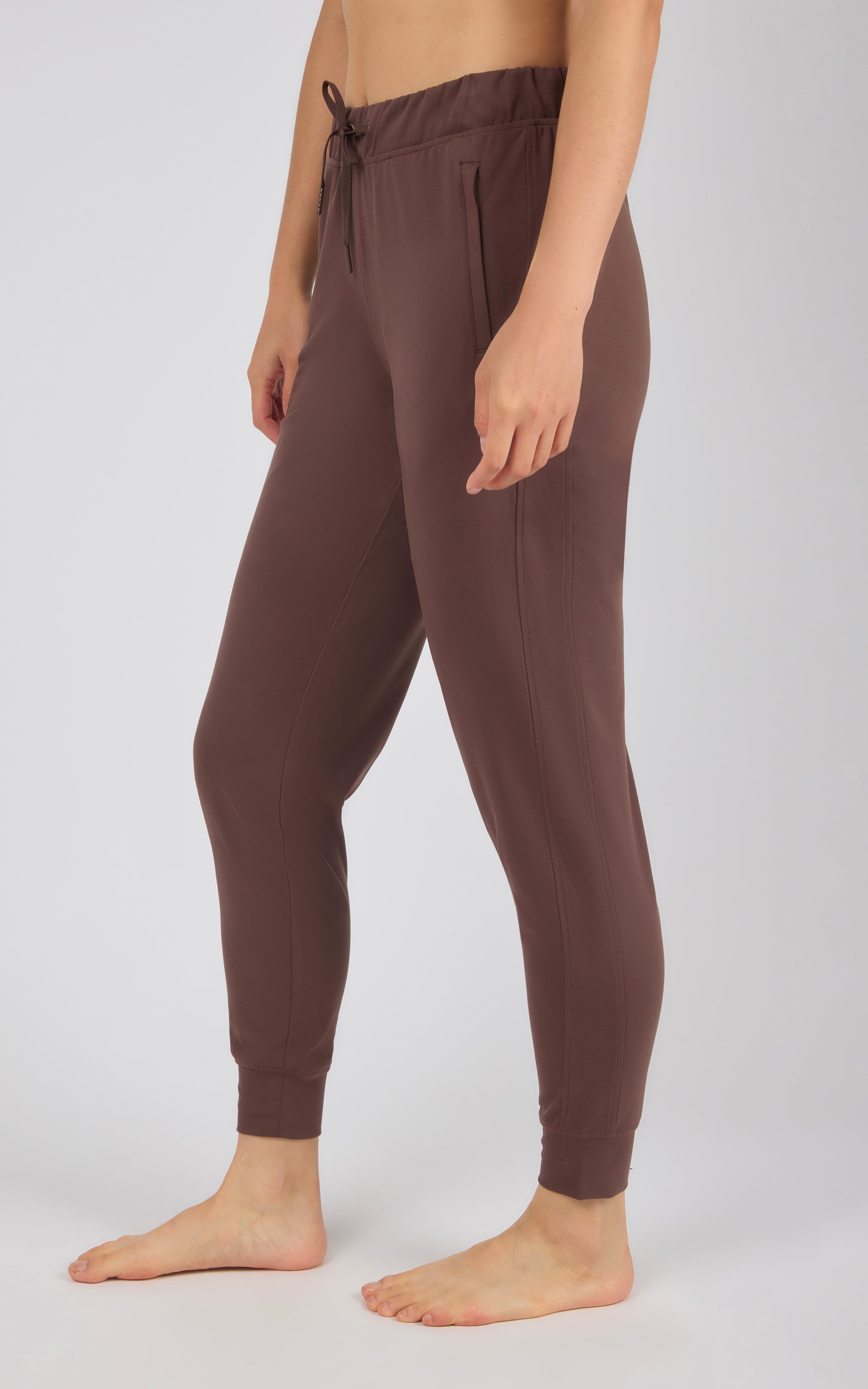 Women's slim-fit joggers in rich chocolate brown with side pockets and ankle cuffs.