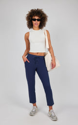 Women's navy straight leg pants with a mid-rise waist and front pockets, styled with a white sleeveless crop top and beige.