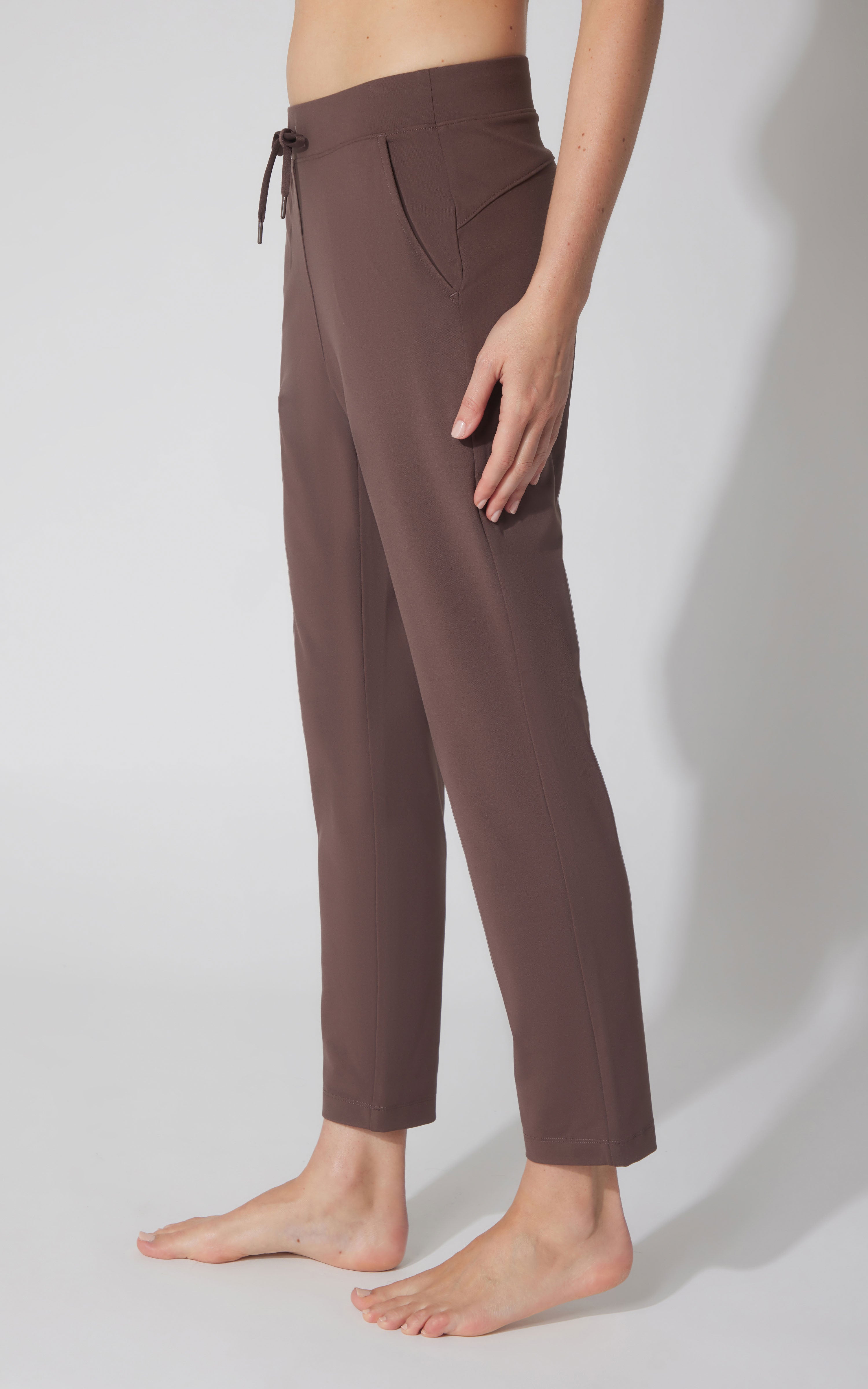 Straight leg chocolate brown pants with a drawstring waist and side pockets, worn barefoot.