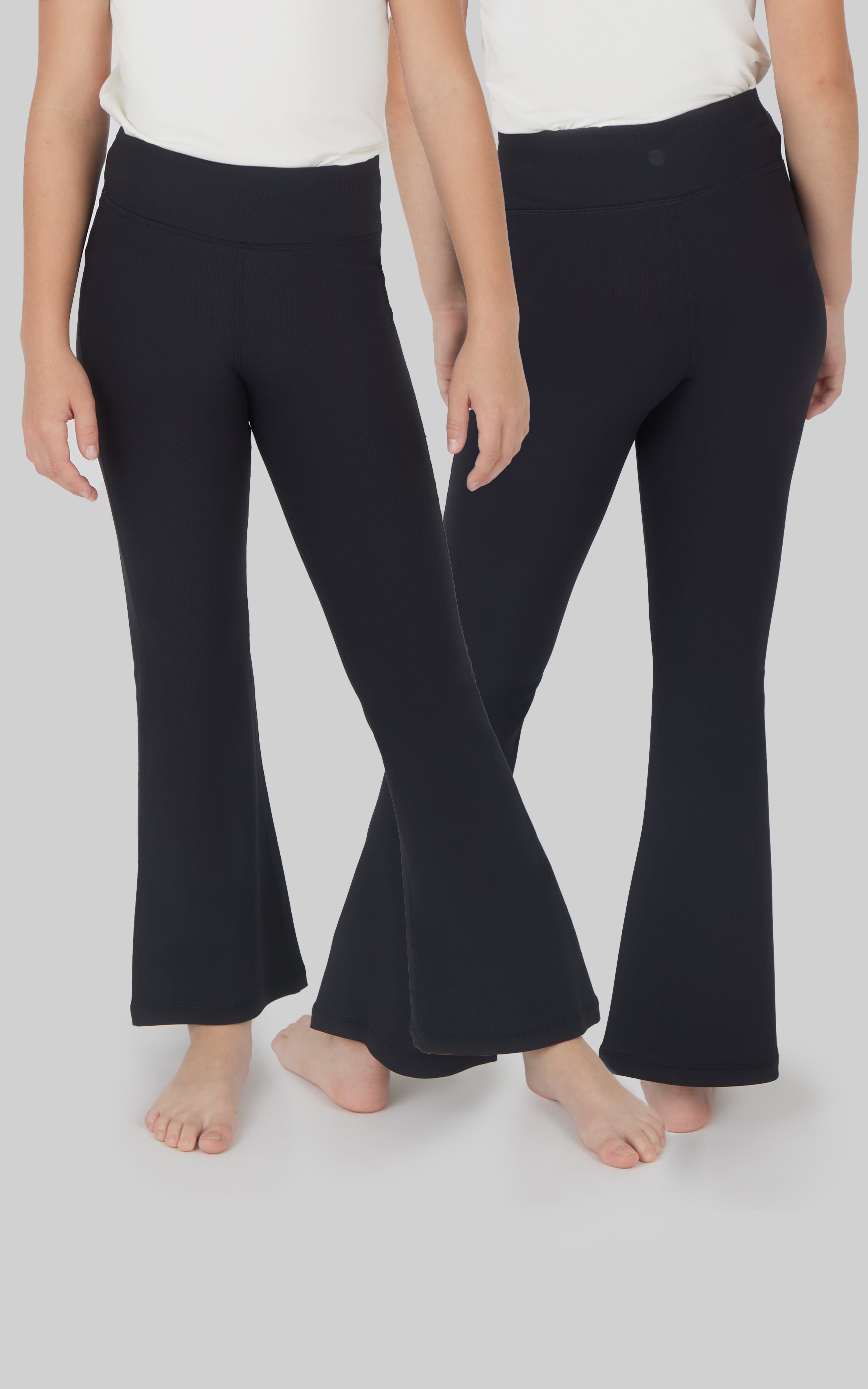 Two pairs of black ribbed flare girls leggings with a soft fleece texture modeled waist down.