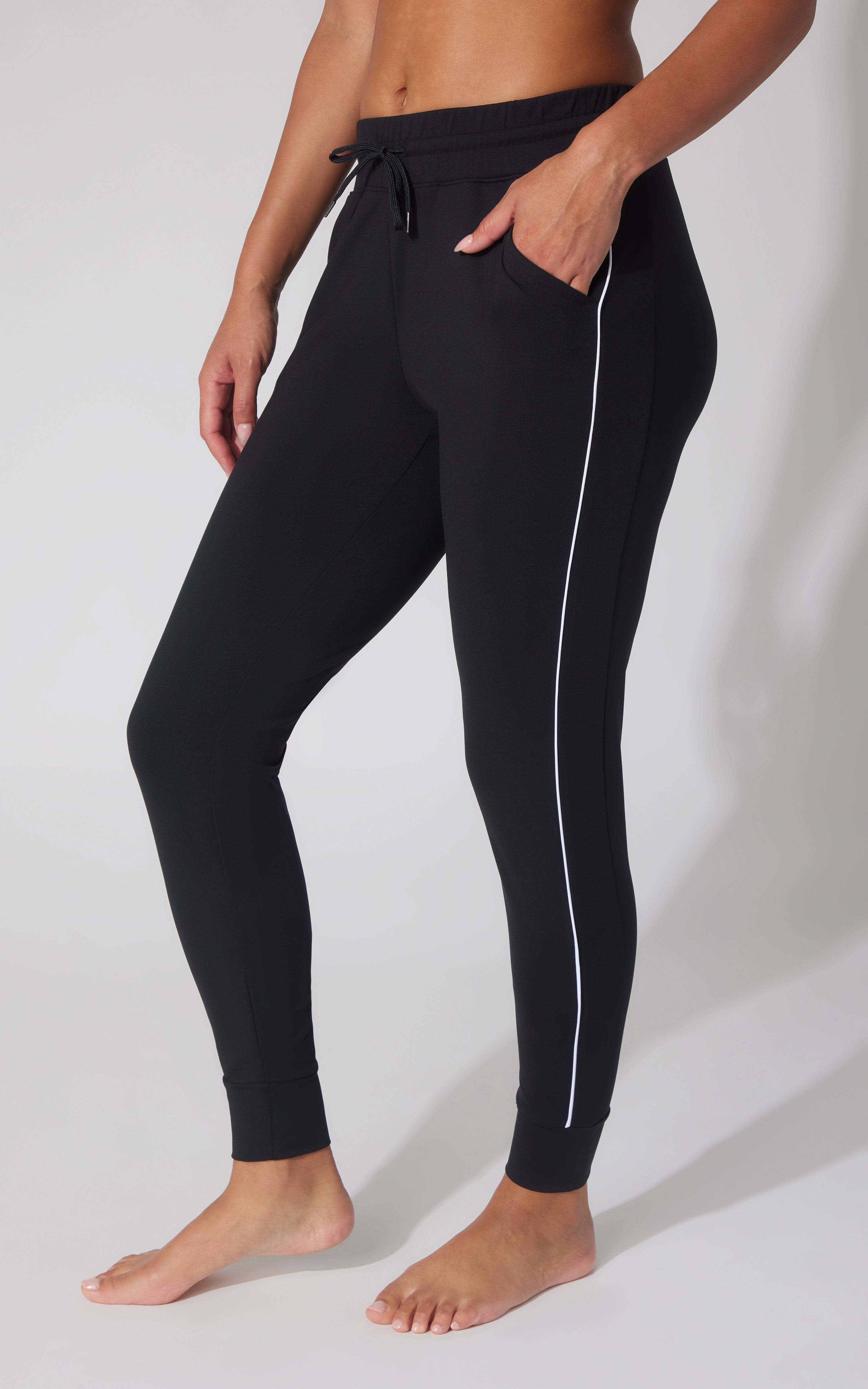Black fleece joggers with white piping along sides, elastic waistband with drawstring, and slim fit.