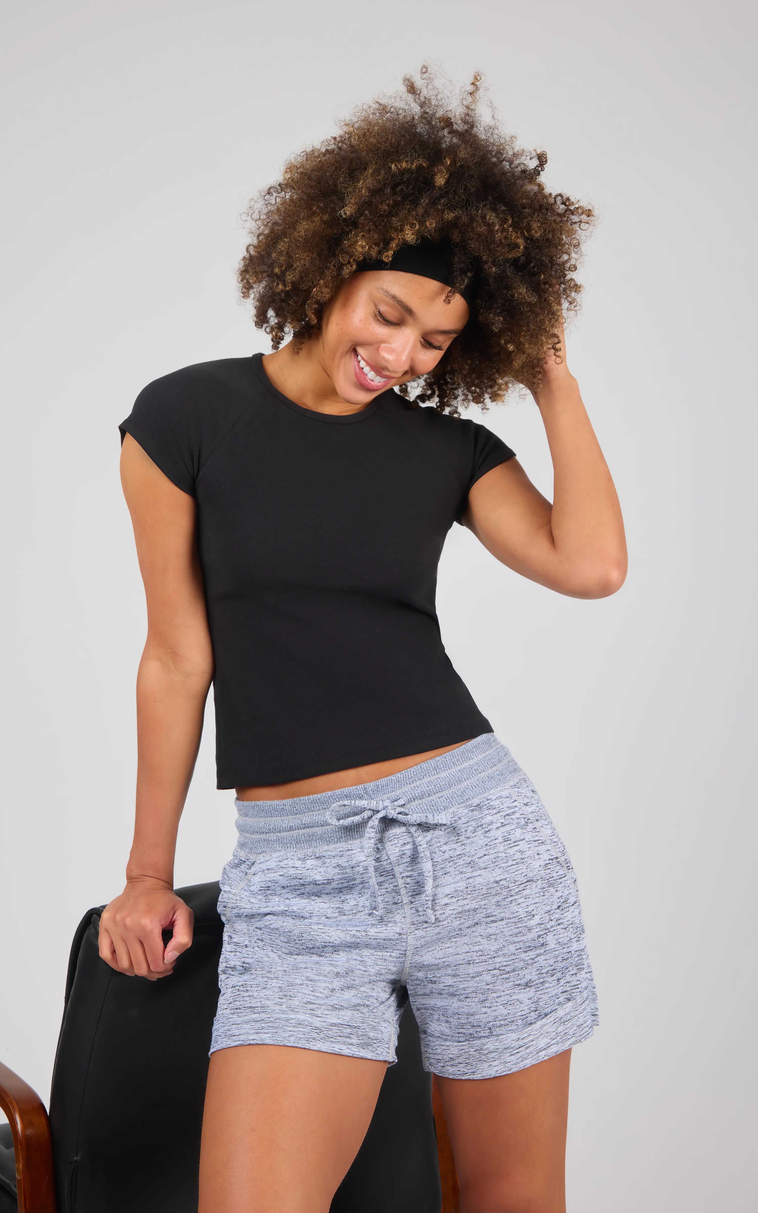 Heather grey soft knit lounge shorts with a drawstring waist and relaxed fit on a smiling model in a black fitted t-shirt.