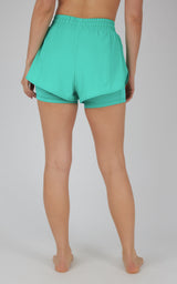 Women's teal lightweight running shorts with elastic waistband and layered hem detail, back view.