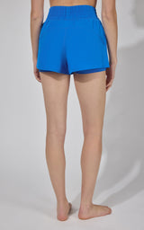 Women's bright blue running shorts with elastic waistband and relaxed fit, back view.