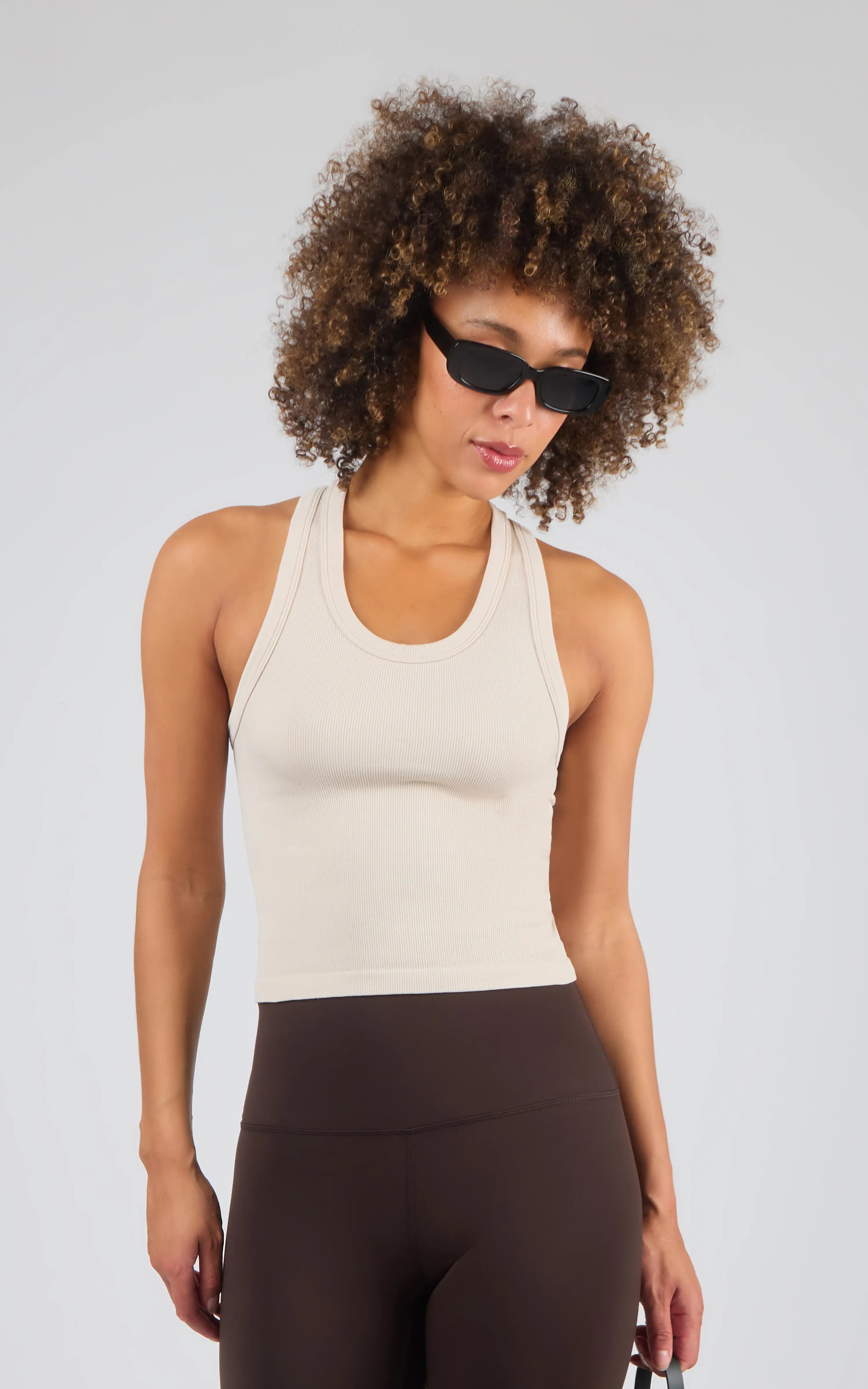 Off-white ribbed racerback tank top with a fitted silhouette and scoop neckline.