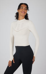 Cream seamless long sleeve top with decorative stitch details on chest and sleeves.