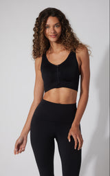 Black seamless full zip sports bra with wide straps and fitted design on a woman.