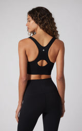 Black seamless full-zip sports bra with racerback and cutout detail on model.