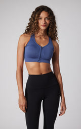 Blue seamless full zip sports bra with racerback and supportive fit on female model.