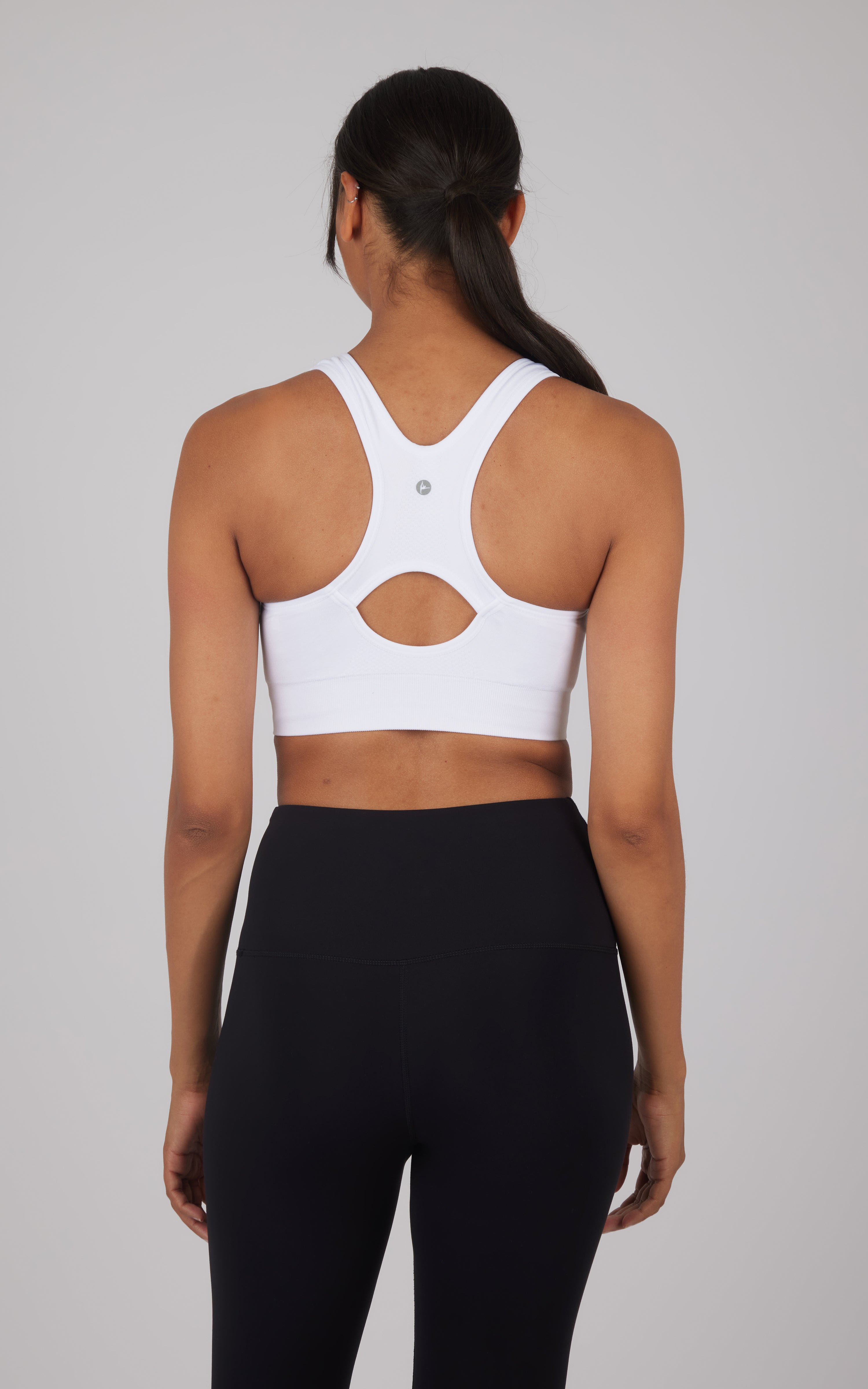 White seamless full-zip sports bra with cut-out detail on racerback, worn with black leggings.