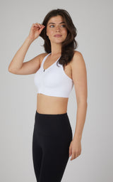 White seamless full zip sports bra with racerback on a slim woman wearing black leggings.