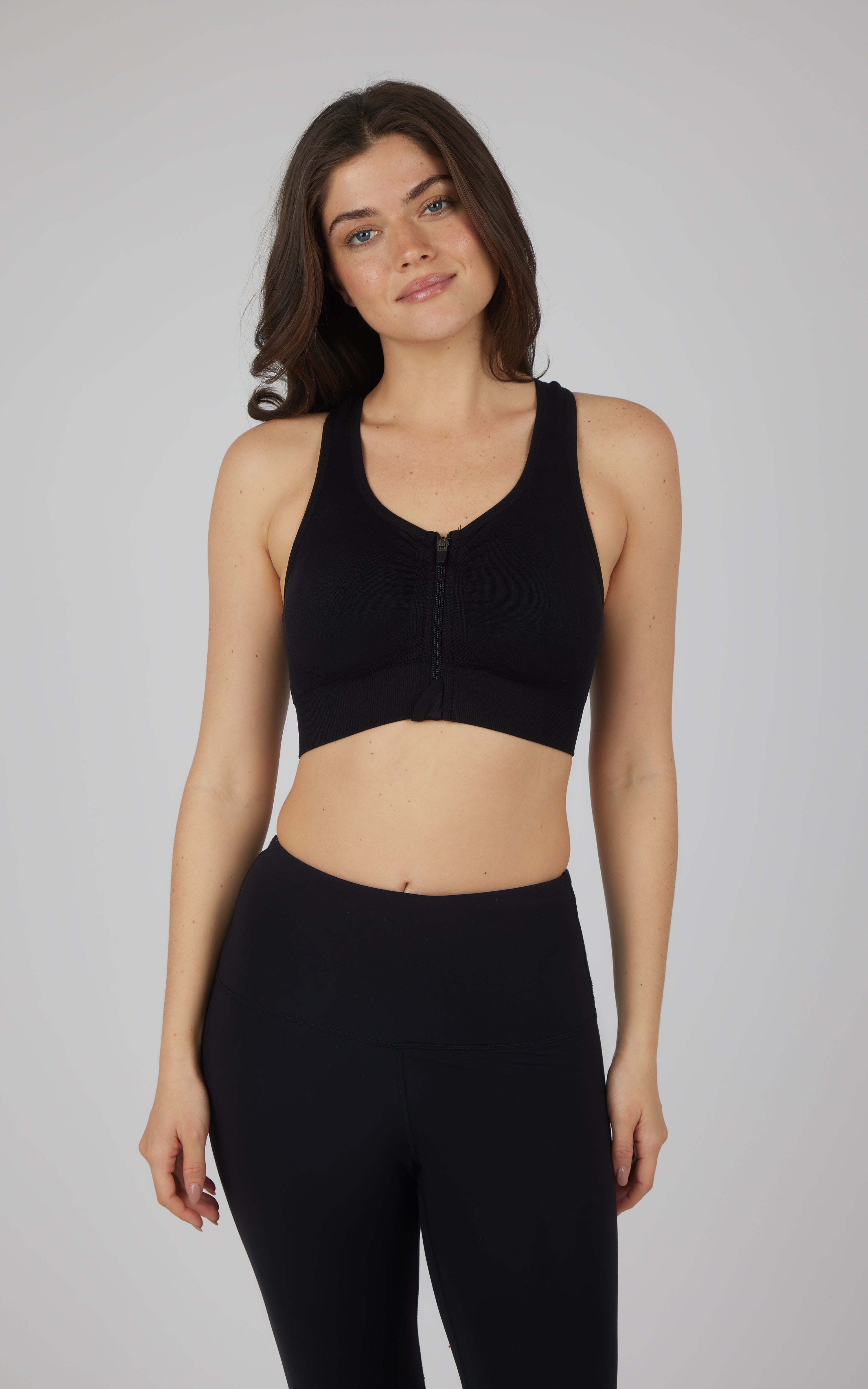 Seamless black full zip bra with racerback design on model.