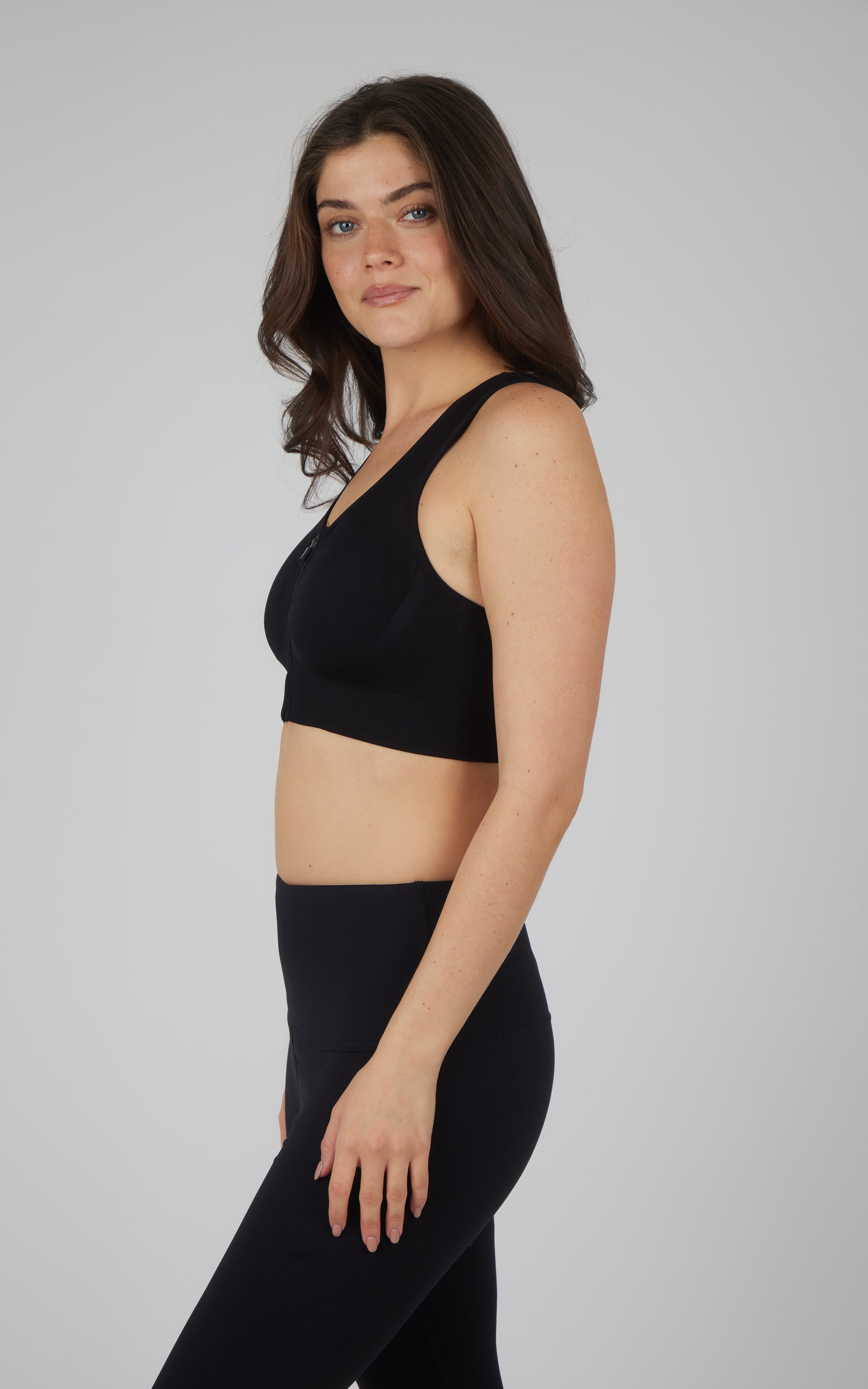 Black seamless full-zip bra with wide straps and smooth fabric on a woman.