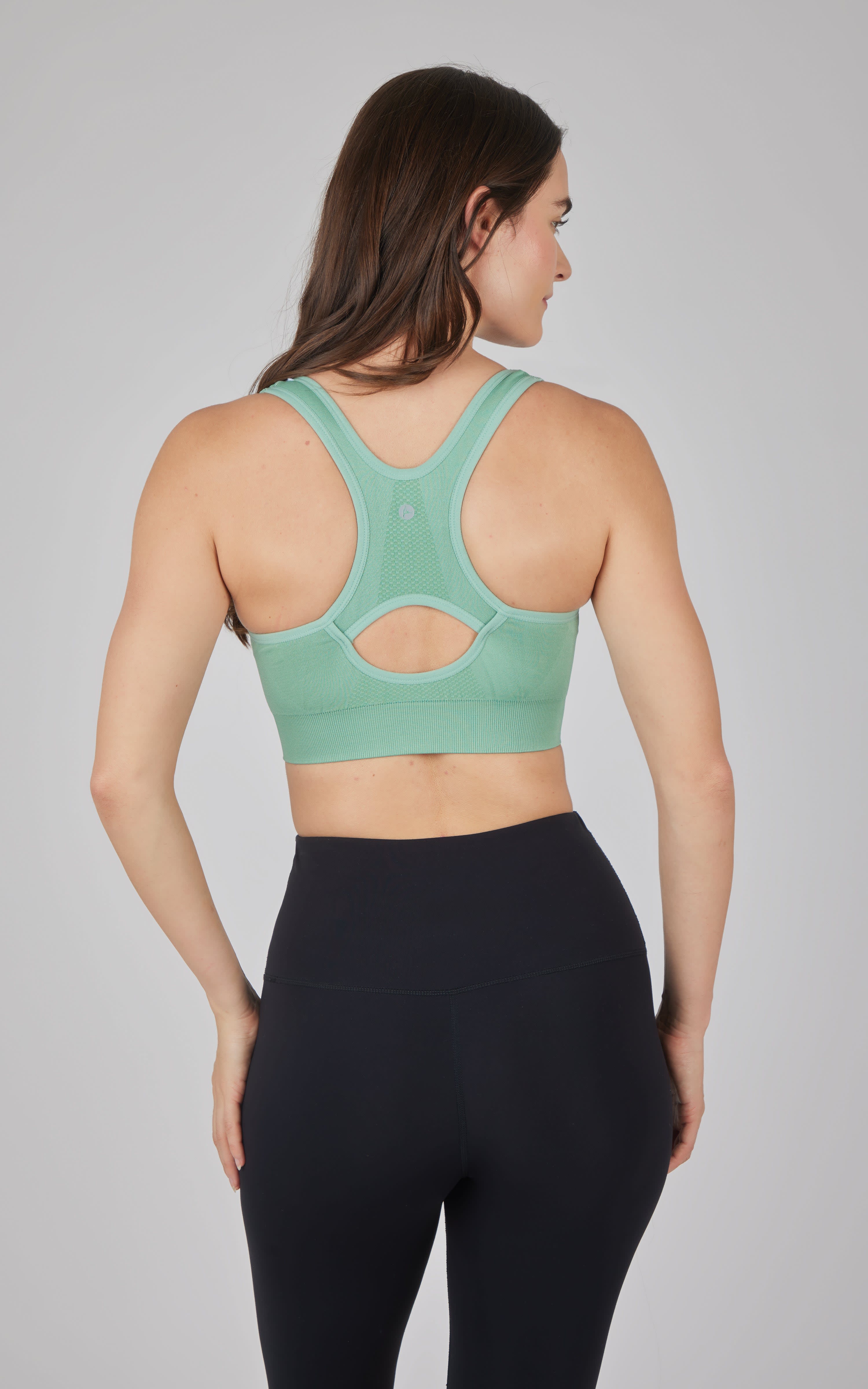 Seamless teal full zip sports bra with racerback and cutout design.