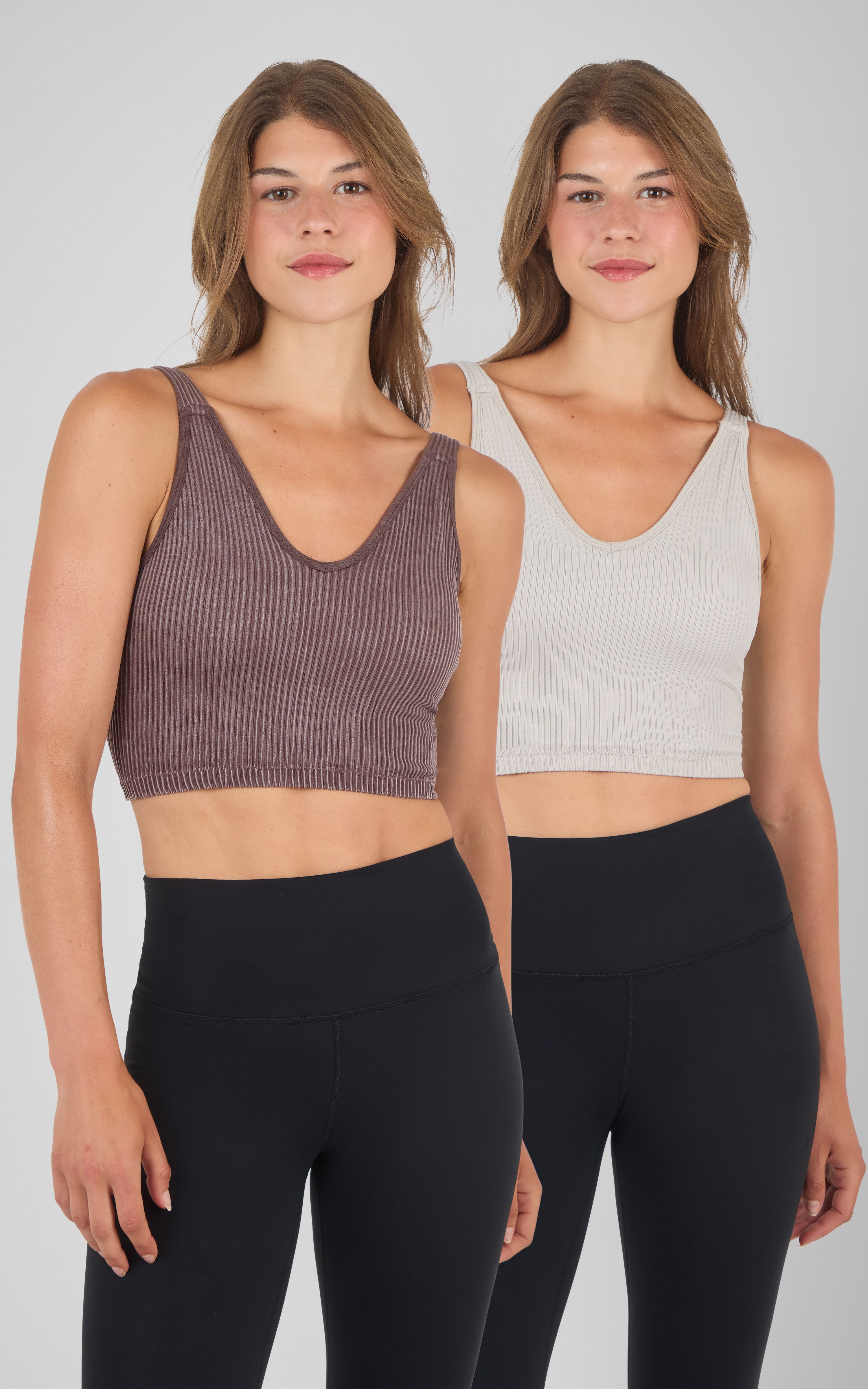 Two women wearing seamless ribbed Alamo bra tanks in brown and light gray, paired with black leggings.