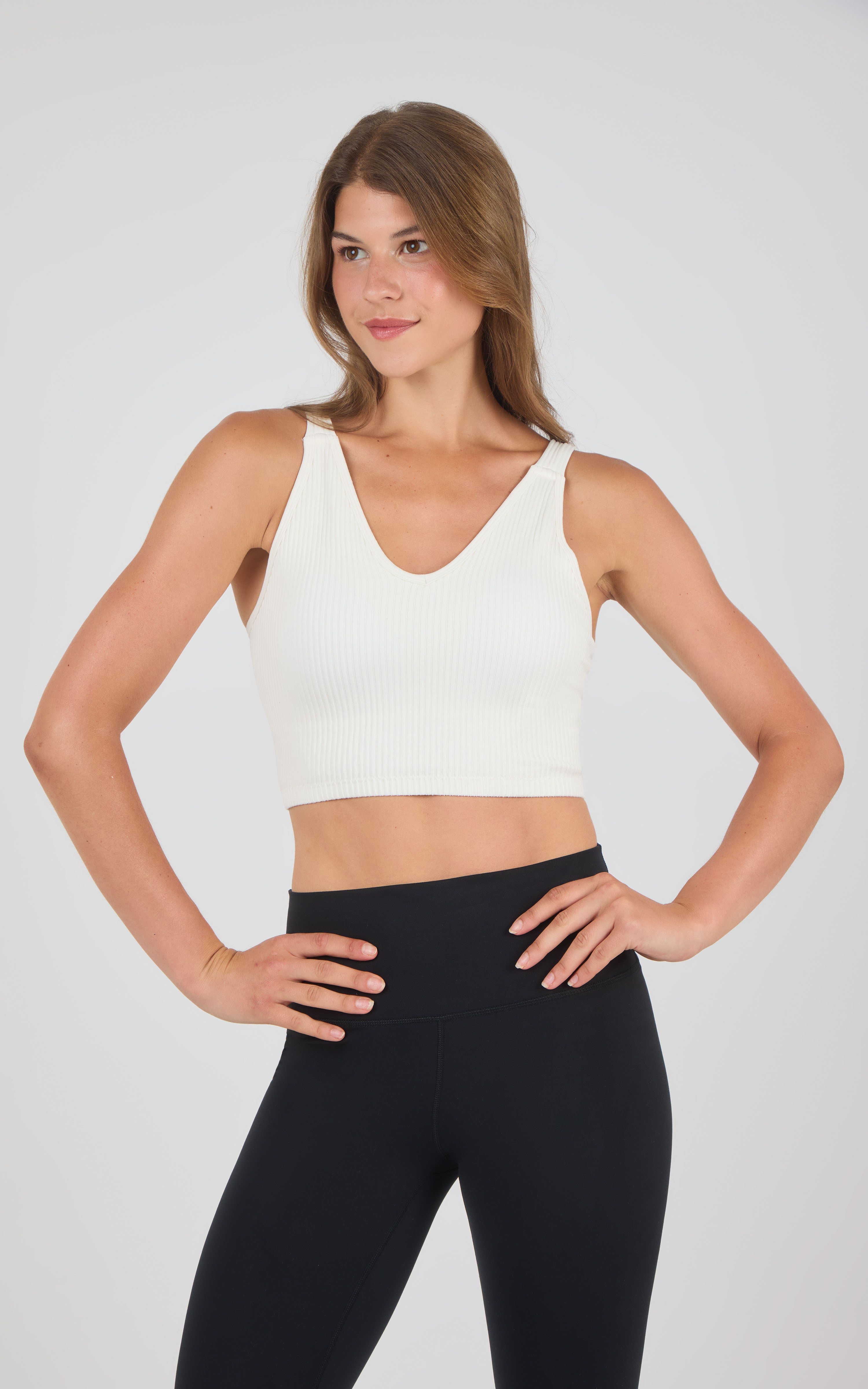 Seamless ribbed cream-colored bra tank with wide straps and V-neckline on model.