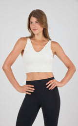 Seamless ribbed cream-colored bra tank with wide straps and V-neckline on model.