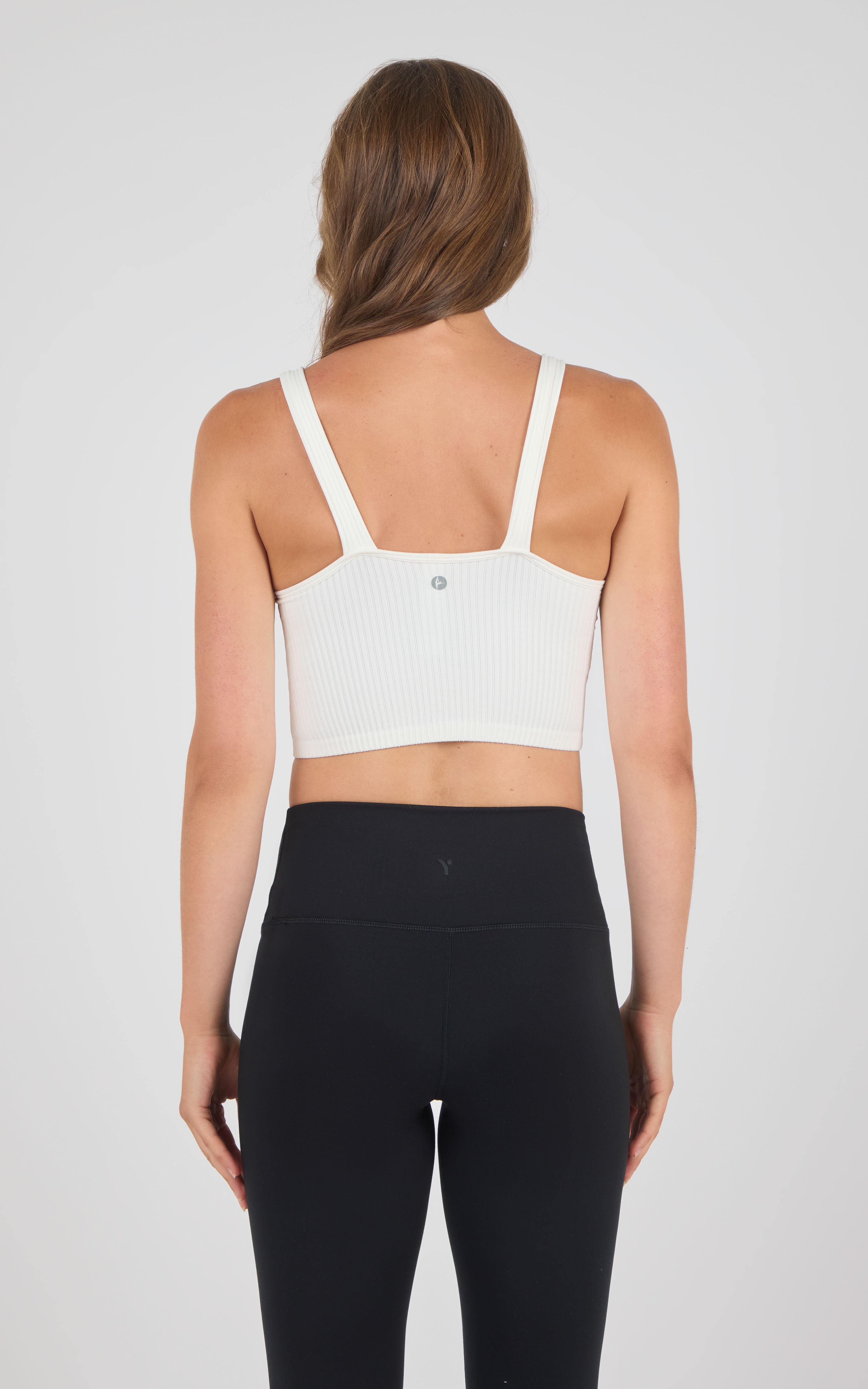 White seamless ribbed bra tank with adjustable straps and small back logo detailing.