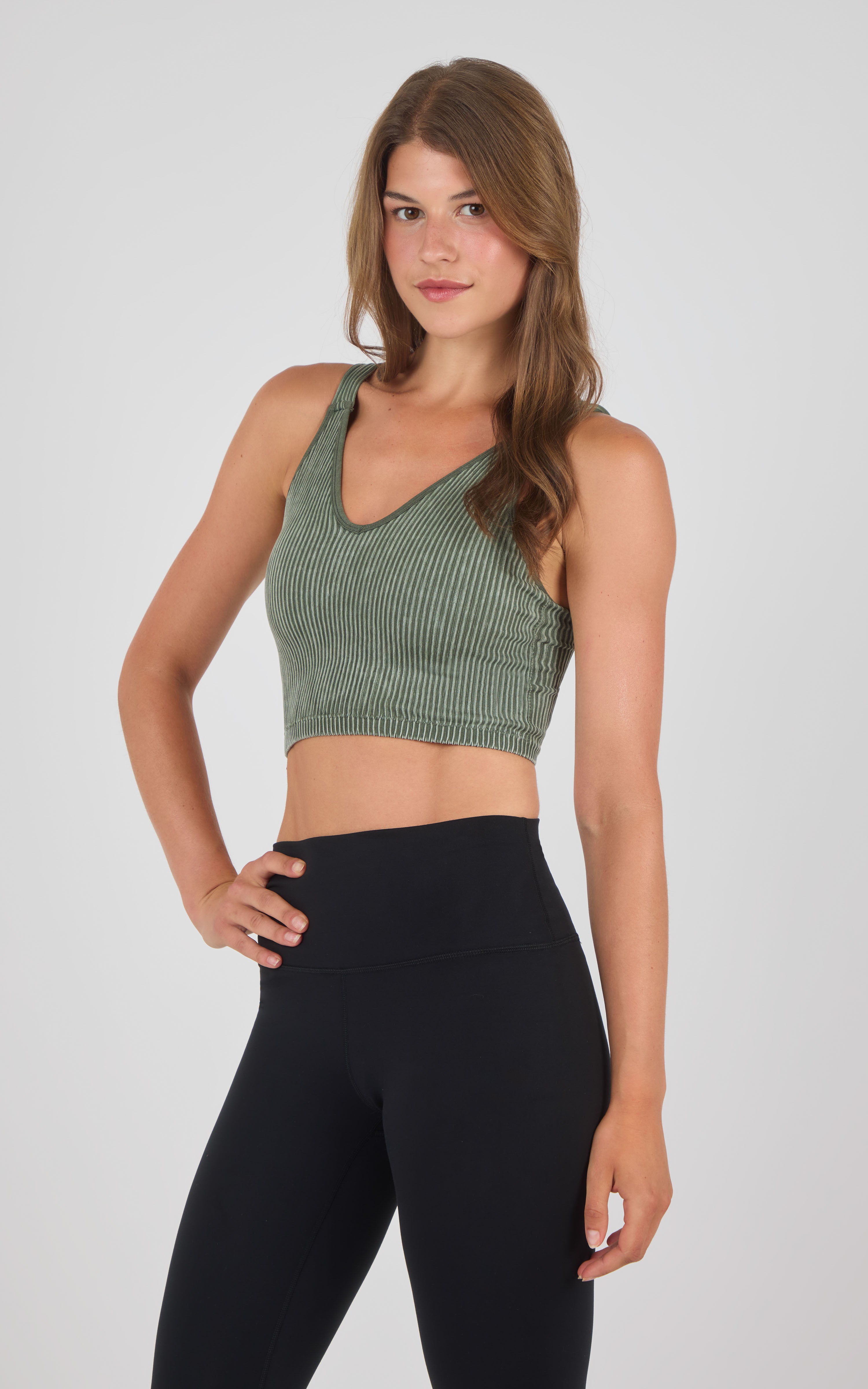 Olive green seamless ribbed bra tank with wider straps and V-neck, paired with high-waisted black leggings.
