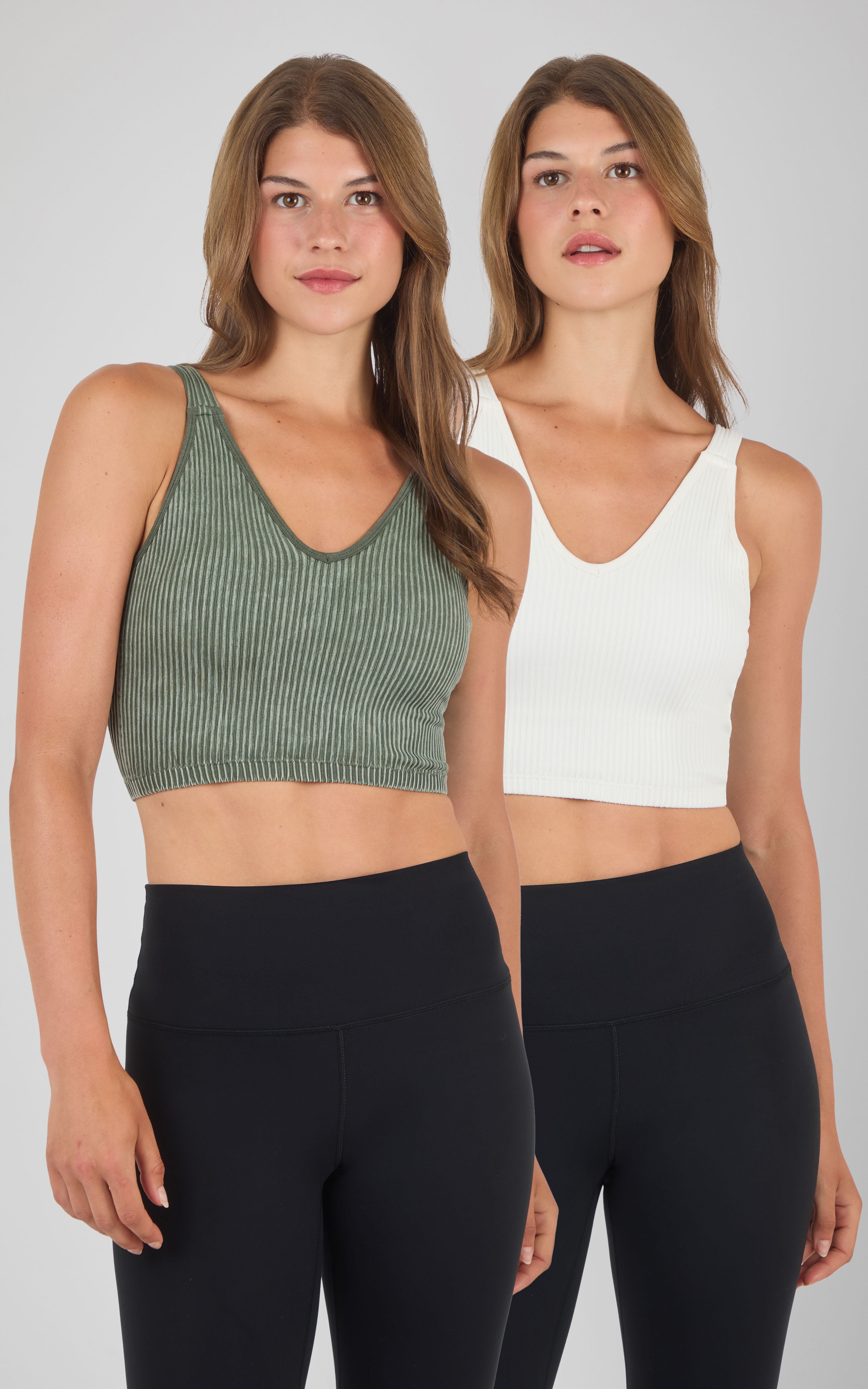 Two women wearing seamless ribbed bra tanks, one in olive green and one in off-white, paired with black leggings.
