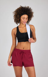 Black seamless textured zip-front bra top with wide straps and a square neckline worn with burgundy drawstring shorts.