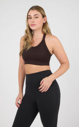 Woman wearing a black stonewashed ribbed scoop-neck bra tank with wide straps and a cropped fit.