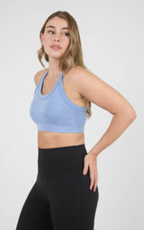 Woman wearing a light blue ribbed scoop-neck bra tank with wide straps and a cropped fit.
