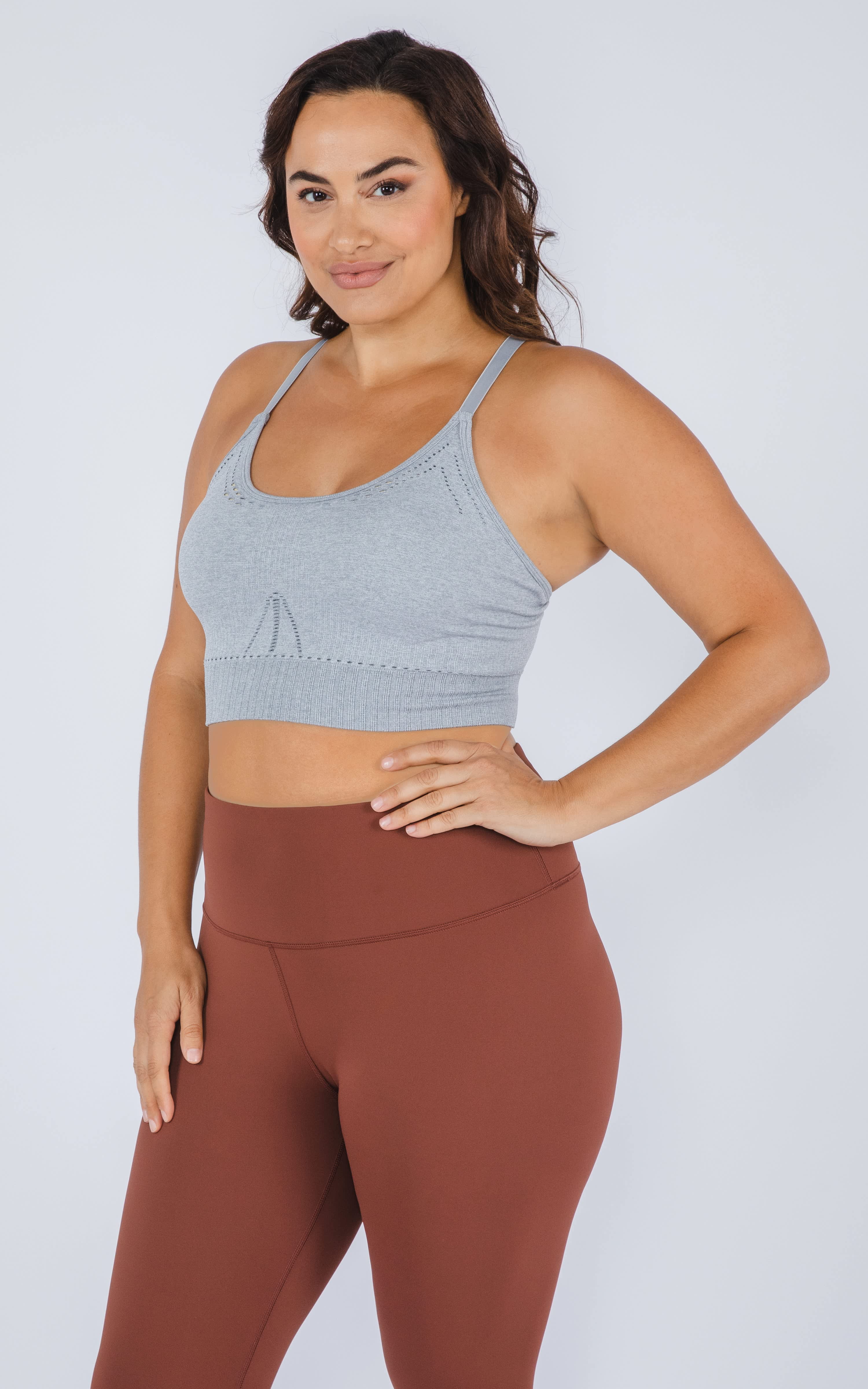 Plus size seamless racerback sports bra in heather gray with keyhole detail, worn with brown leggings.